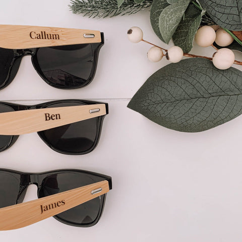 Bamboo sunglasses with a name engraved on the arm, shown in natural light