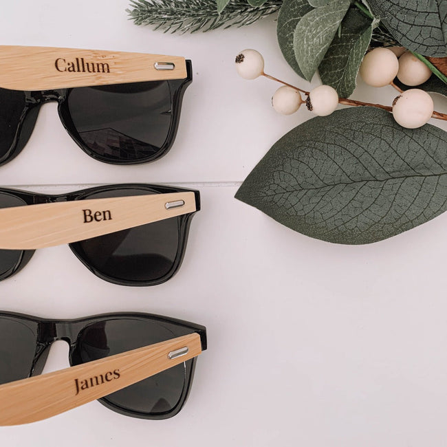 Bamboo sunglasses with a name engraved on the arm, shown in natural light